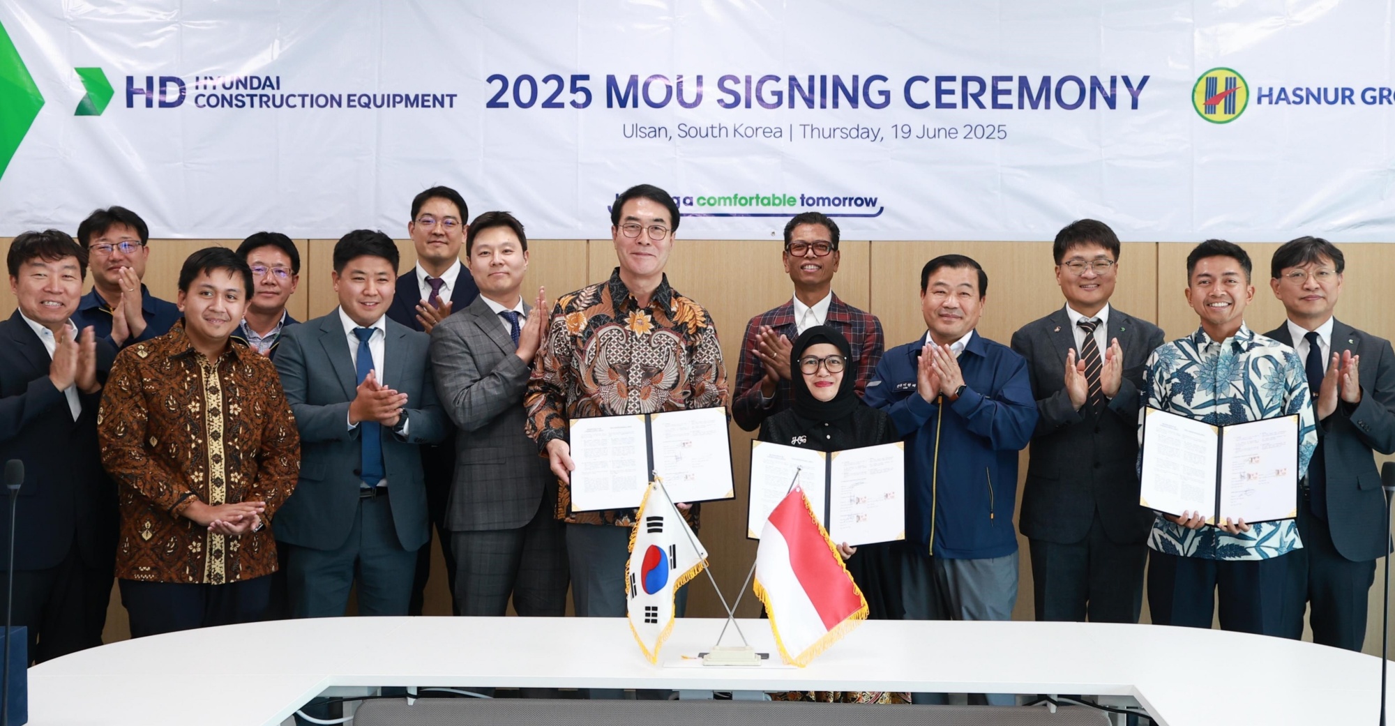 HD Hyundai Construction Equipment President Choi Cheol-gon (fifth from the left in the front row) and Hasnur Group President Jayanti Sari (sixth from the left in the front row) pose for a commemorative photo following the signing of the strategic business agreement at the Ulsan Campus on the 19th.